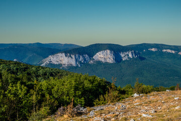 View from the top of the hill to the mountains with a forest on a summer day.