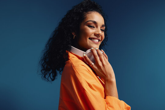 Happy young woman with headphones in vibrant colorblocking background, showcasing creativity and joy