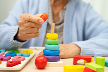 Alzheimer disease AD, Asian elderly woman patient suffering from dementia learn practical motor skills rehabilitation.