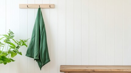 Green Cloth Hanging on Hook Against Minimalist White Wall Background