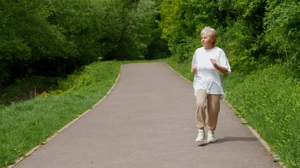 A Senior Woman is Jogging in a Beautiful Park Surrounded by Lush Greenery and Vibrant Nature