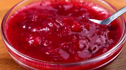 Bright red cranberry sauce taking with a spoon close up