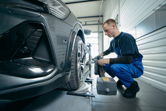 Auto mechanic adjustment automobile wheel alignment work at repair service station