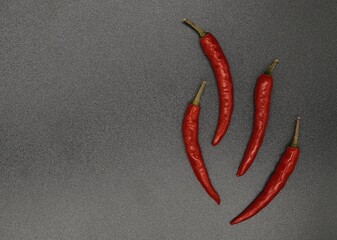 four pods of red hot pepper on a dark background