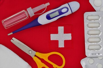 thermometer, medicines, bandage, scissors, drops in a bottle on the background of a first aid kit
