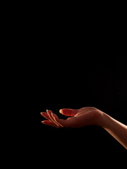 woman's hand palm facing up, black background