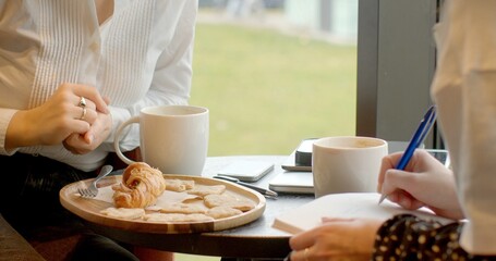 Two individuals enjoying coffee and pastries in a bright caf setting