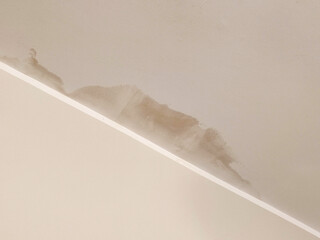 A ceiling with visible water stains and discoloration caused by a leak, indicating water damage and...