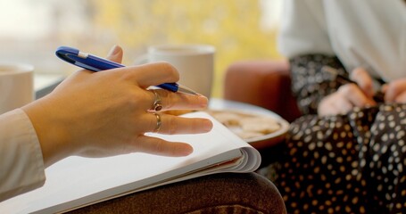 Psychotherapist takes notes about patient condition on paper during session. Close-up of pen and paper. Makes written records of progress and insights during the therapy session. People lifestyle.