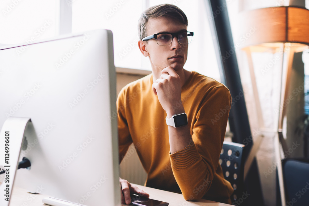 Poster caucasian hipster guy pondering on wireless connection on computer staying on office desktop, young 
