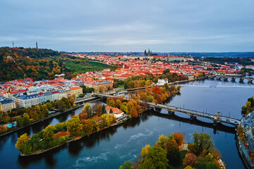 Aerial view of cityscape of Prague with colorful autumn trees on island on Vltava river. Architecture of Praha, Czech Republic