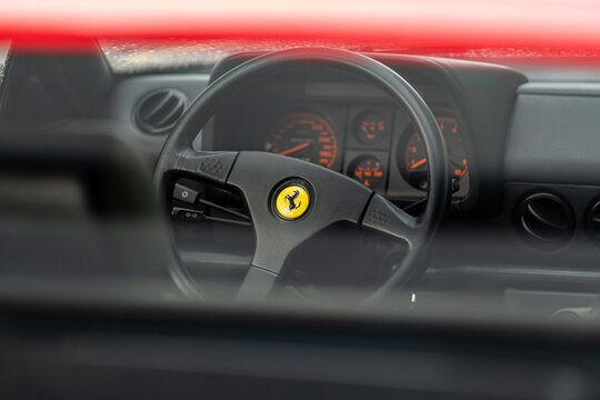 Red Ferrari 512 Testarossa sports car, detail of steering wheel and car interior. Classic luxury racing car.