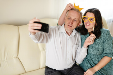 Husband and wife having fun together. Selfie with accessories. party props