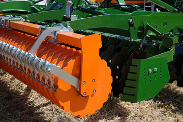 Close-up of a large modern plow orange color or disc harrow for cultivating the land.