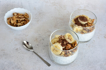 a drinking glass with healthy snack of bananas, chia and oatmeal are on a table 