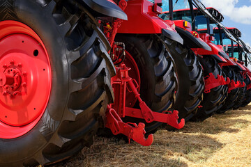 Several large modern red tractors standing in a field.