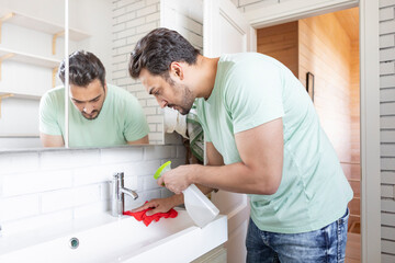 Close up of man cleaning faucet and sink in the bathroom	