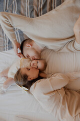 Portrait of mom, dad and child on top of the bed lying