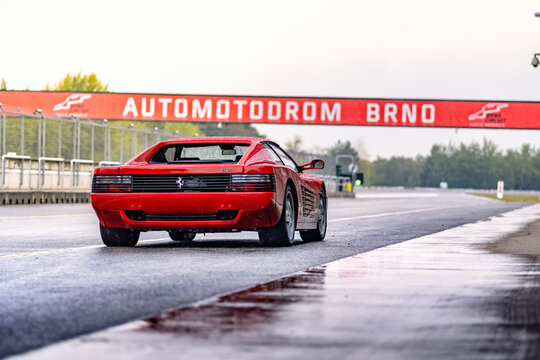 Red Ferrari 512 sports car on the race track. Fast luxury classic car Ferrari Testarossa parked outside.