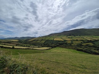 Obraz premium Mountain Landscape Under Cloudy Sky with Grassland Terrain