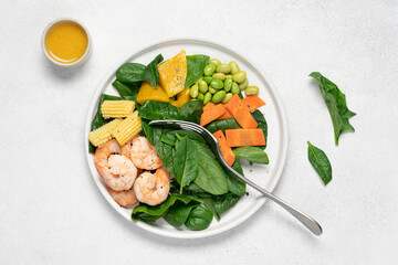 Shrimp salad with spinach, edamame beans, carrot, corn, mango on white background. Healthy food  concept