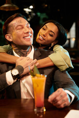 A young couple enjoys a joyful evening together at a vibrant bar setting.