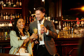 A young multicultural couple enjoys cocktails while laughing and having a fun night out.