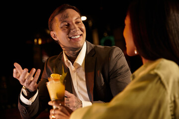 Tattooed young couple shares laughter and drinks during a delightful night out.