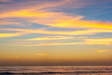 Obraz premium Dramatic Sunset Over Calm Ocean With Vibrant Clouds In The Sky