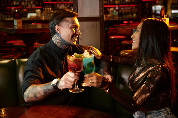 A young couple shares laughter and drinks at an upscale bar during a fun evening together.