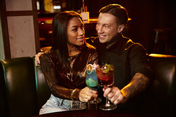 A young couple shares laughter and cocktails, soaking in the vibrant nightlife at a bar.