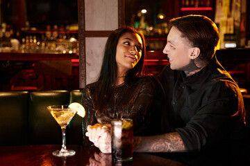 A young couple shares a cozy moment at a lively bar, immersed in nightlife and connection.