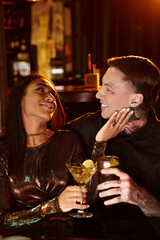 A beautiful young couple shares drinks and laughter on their evening date at a lively bar.