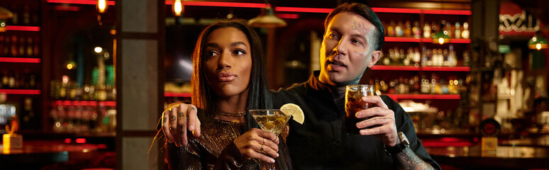 Young couple shares laughter and drinks during a fun night out at a lively bar.