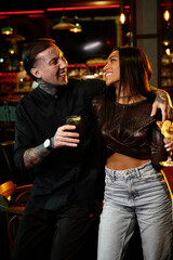 A multicultural couple enjoys joyful moments at a trendy bar, celebrating love together.