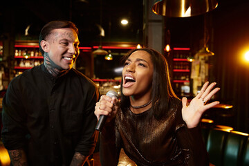 A young couple shares laughter and music while enjoying their night out at a bar.