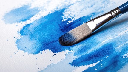 Close-up of a paintbrush on a canvas with vibrant blue watercolor strokes.