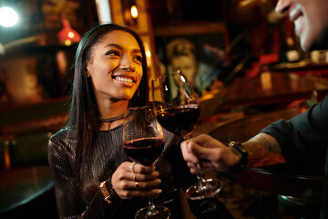 A young couple shares a joyful moment while clinking their wine glasses during a date.