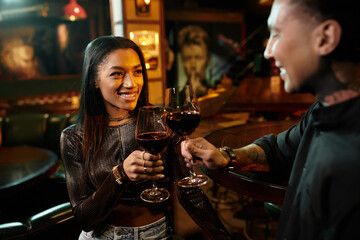Young couple toasting with glasses of wine during their vibrant night out in the bar.