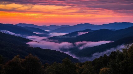 Obraz premium A silhouette of mountains against a colorful sunrise sky, with layers of clouds and mist creating a dramatic and serene scene, perfect for nature enthusiasts