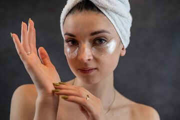 young cute girl in white towel clean skin with black silicone patches isolated on black background