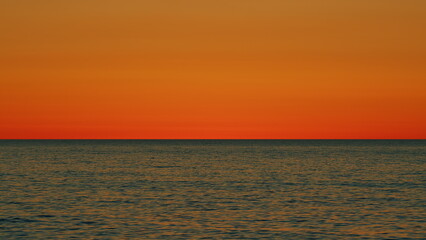 Golden Glare On Water Abstract Background. Sunset At Sea. Ocean Colors Sky And Waves In Red Color. Slow motion.