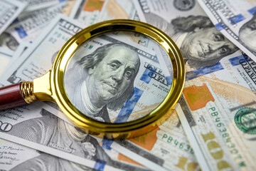 closeup of 100 US Dollar banknotes under magnifying glass