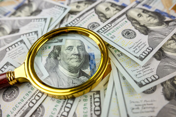 closeup of 100 US Dollar banknotes under magnifying glass