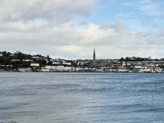 Fototapeta premium Cobh city in Cork county of Ireland, urban cityscape as it is seen from the island, with stormy cloudy sky and ocean
