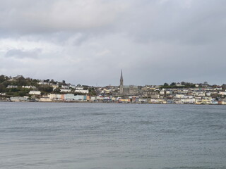 Fototapeta premium Cobh city in Cork county of Ireland, urban cityscape as it is seen from the island, with stormy cloudy sky and ocean