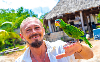 Man with green parrot on his hand arm Solferino Mexico.