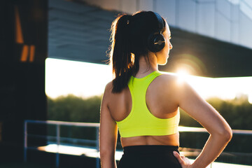 Back view of athletic girl with perfect muscular body shape enjoying workout break, rear of...