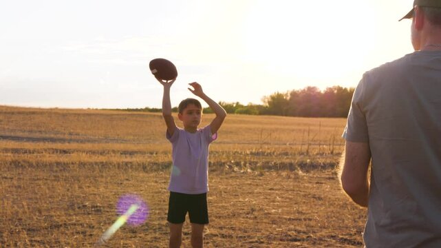 Happy family playing ball: boy and father play american football. boy rugby ball passes dad in an outdoor activity. Experience the joy of family fun and teamwork