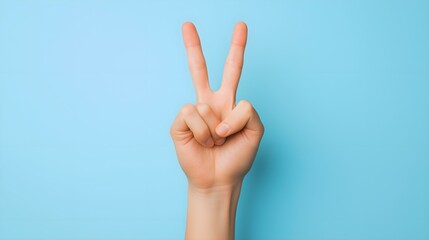 A hand displayed in a peace sign against a light blue background, symbolizing harmony and positivity. This image conveys a message of peace and unity.